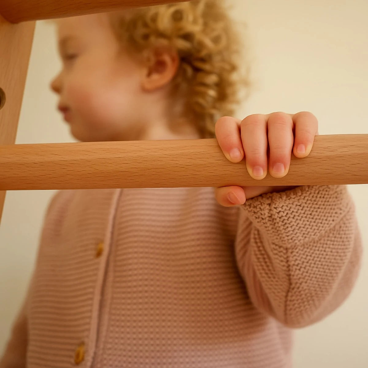 A child holding the smooth wooden rung of a Riababy playhouse