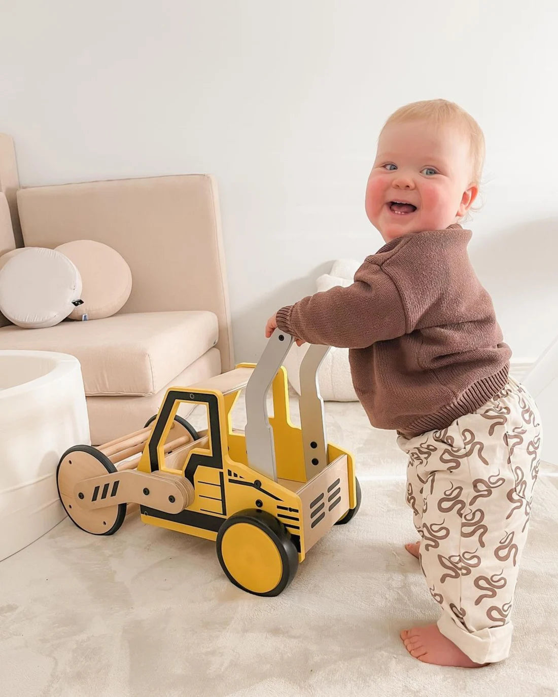 A smiling toddler holding their Riababy RoadRoller walker