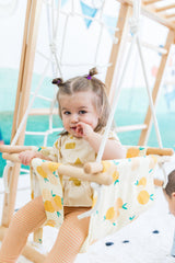 Close-up of a child in a swing with large yellow lemon print