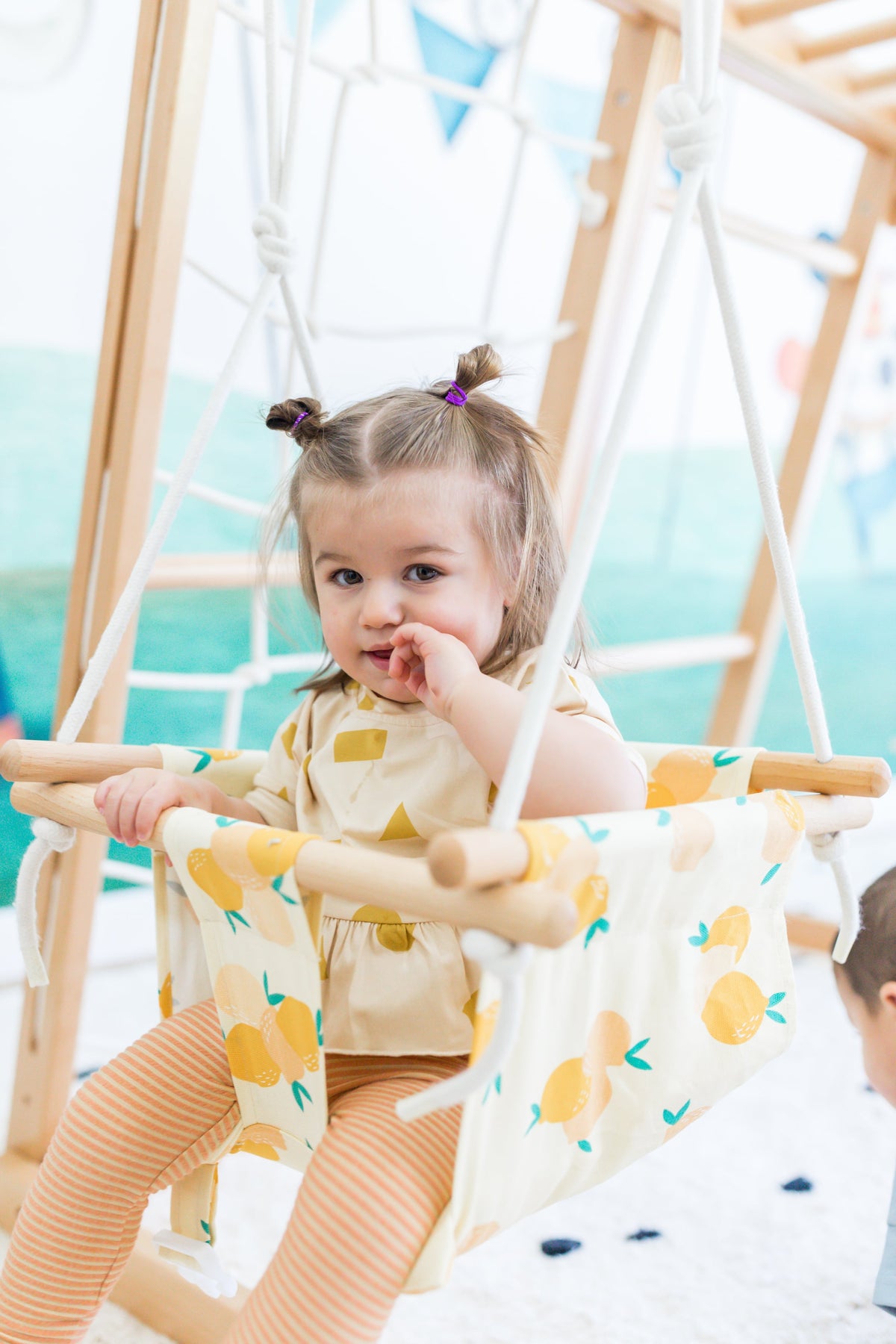 Close-up of a child in a swing with large yellow lemon print
