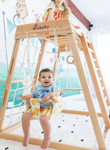 Child in a large lemon-print swing beneath a Kangaroo frame, with another child above