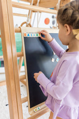Child using the black side of the double-sided magnetic drawing board on a Kangaroo Playhouse