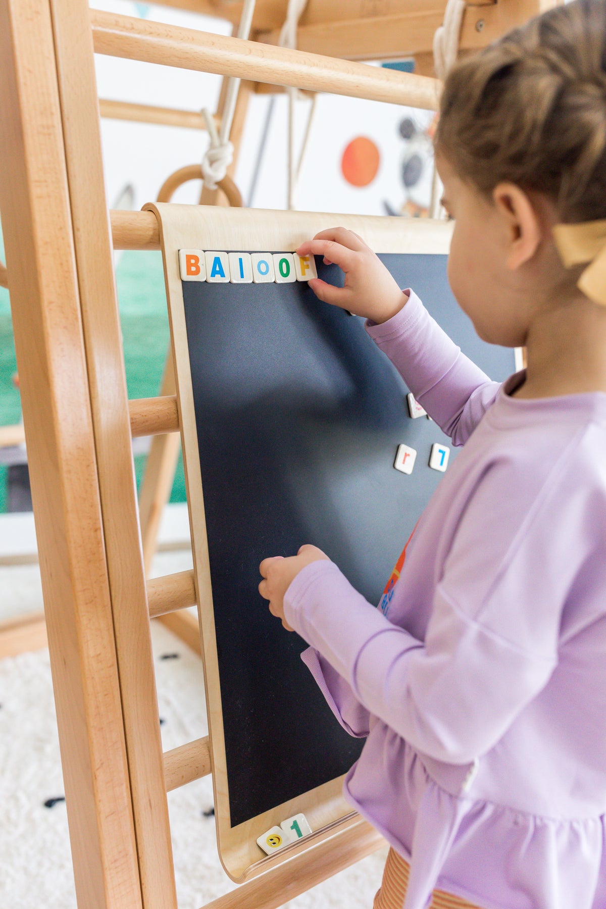 Child using the black side of the double-sided magnetic drawing board on a Kangaroo Playhouse