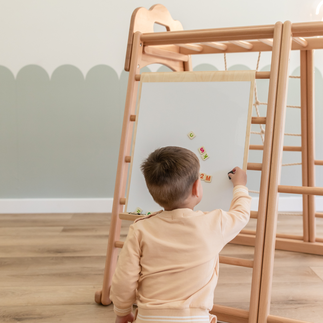 Child using the white side of the magnetic drawing board attached to a Koala Playhouse