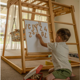 Child using magnetic letters and numbers on the white side of the drawing board attached to a Kangaroo Playhouse