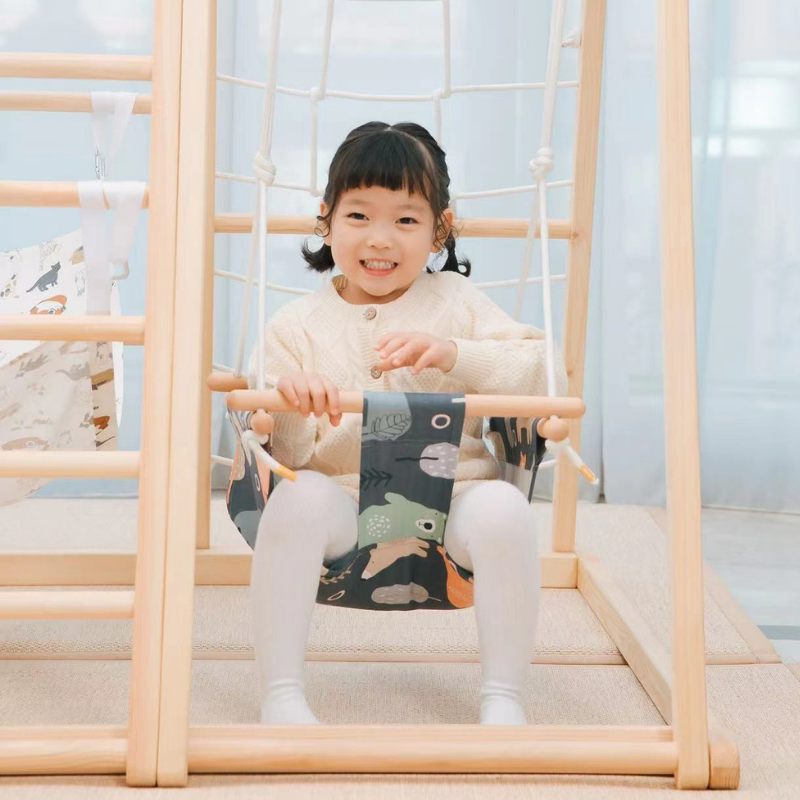 Child sitting in a Happy Bear swing attached to a Kangaroo playhouse
