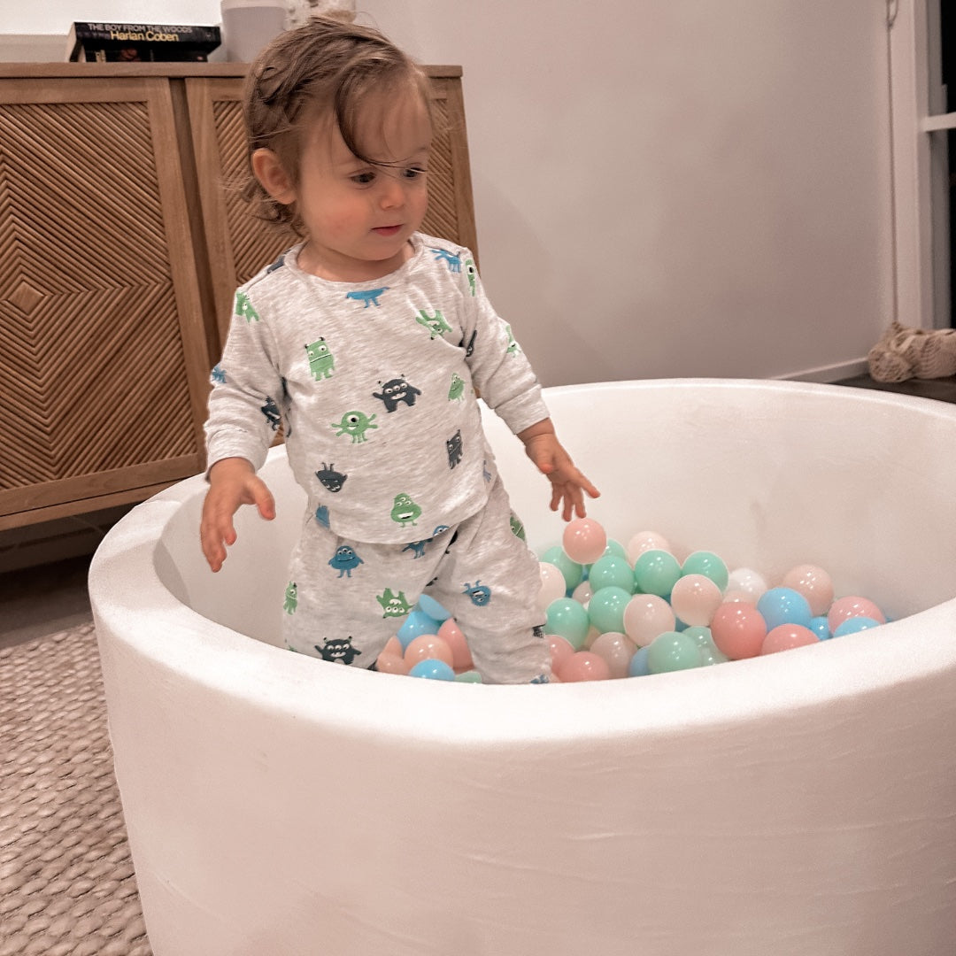 Child playing in a fabric-covered white foam ball pit
