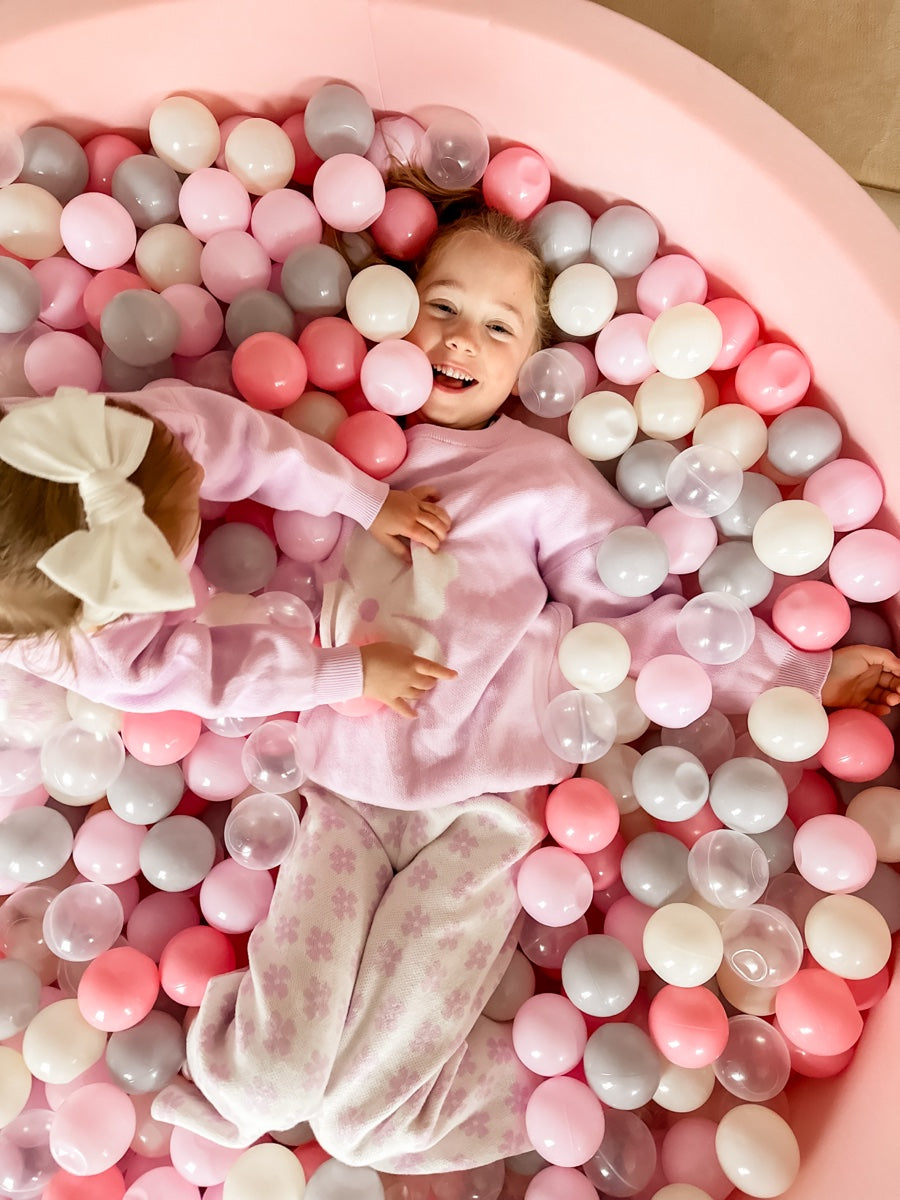 Family playing in a pink round ball pit