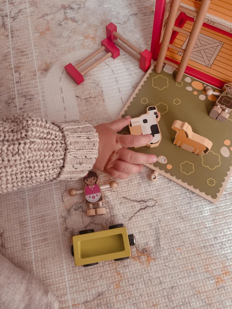 Small hands making up a story with Riababy wooden farm animals